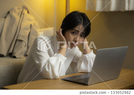 看一台計算機的少婦在客廳在晚上 看一台計算機的少婦在客廳在晚上 133052982