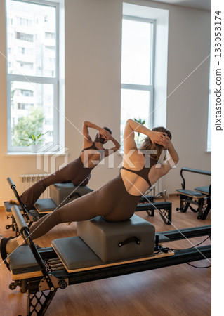 Balancing side plank during Pilates, Female Pilates trainer performs controlled side plank Balancing side plank during Pilates, Female Pilates trainer performs controlled side plank 133053174
