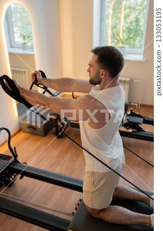 Kneeling pulley exercise, practicing on reformer pulley row focusing on shoulder control Kneeling pulley exercise, practicing on reformer pulley row focusing on shoulder control 133053195