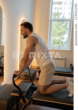 Close up hand man Core body muscles, man doing Pilates exercises to strengthen body and stretch. practicing physical fitness exercises on Pilates machine. Reformer pilates studio machine for workouts 133053200