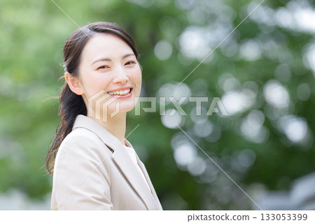 A businesswoman looking to the future, making morning withdrawals or commuting to work, looking at the camera with a green background A businesswoman looking to the future, making morning withdrawals or commuting to work, looking at the camera with a green background 133053399