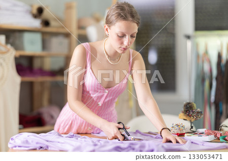 Woman seamstress cutting fabric in sewing workshop 133053471