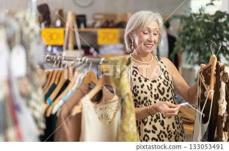 Elderly woman choosing summer clothes in store Elderly woman choosing summer clothes in store 133053491