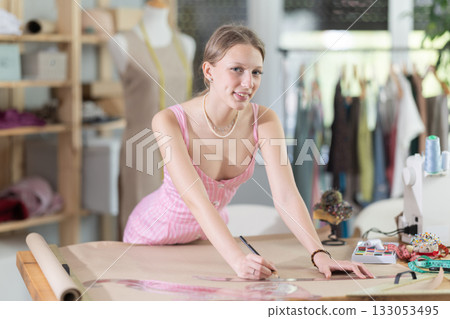 Woman tailor drawing on paper in workshop Woman tailor drawing on paper in workshop 133053495