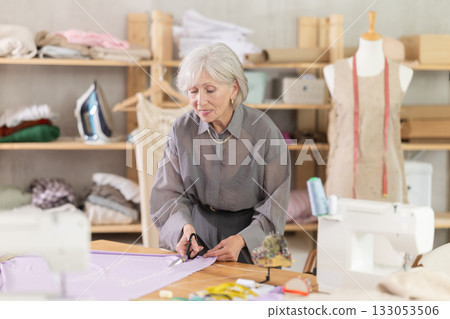 Woman seamstress cutting fabric in sewing workshop Woman seamstress cutting fabric in sewing workshop 133053506