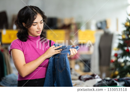Asian woman chooses jeans against the background of the Christmas tree 133053518