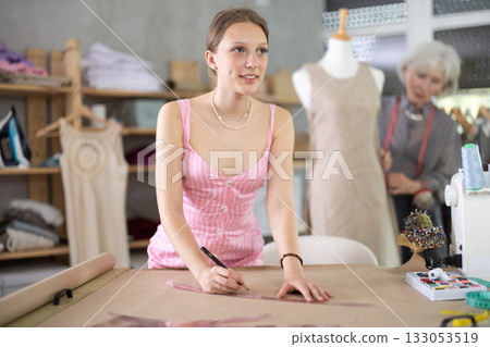 Woman tailor drawing a sketch of clothes on brown paper Woman tailor drawing a sketch of clothes on brown paper 133053519