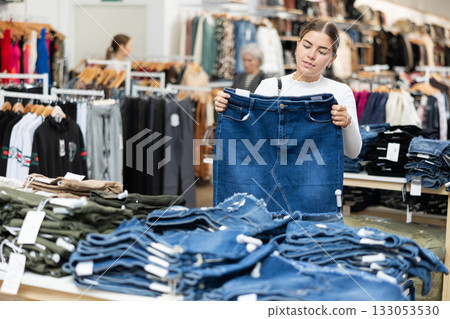Young girl choosing jean skirt in clothing store Young girl choosing jean skirt in clothing store 133053530