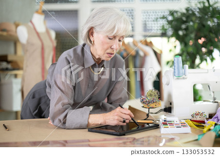 Mature dressmaker drawing sketch on tablet Mature dressmaker drawing sketch on tablet 133053532