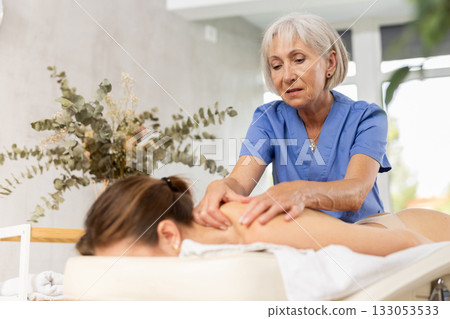 Unrecognizable young woman lies face down and enjoy shoulder massage for body care Unrecognizable young woman lies face down and enjoy shoulder massage for body care 133053533