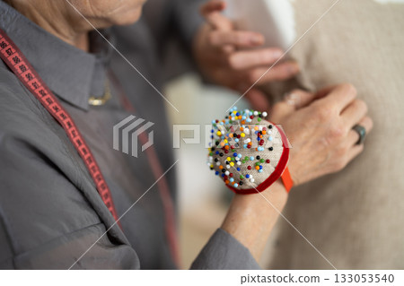 Elderly woman's hands sewing on mannequin Elderly woman's hands sewing on mannequin 133053540