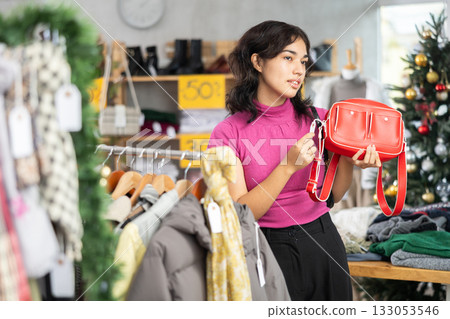 Female shopper chooses a fashionable handbag in clothing store 133053546