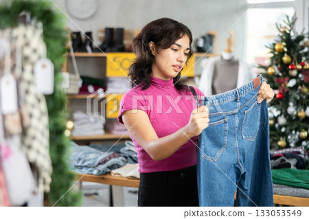 Asian woman chooses jeans against the background of the Christmas tree 133053549