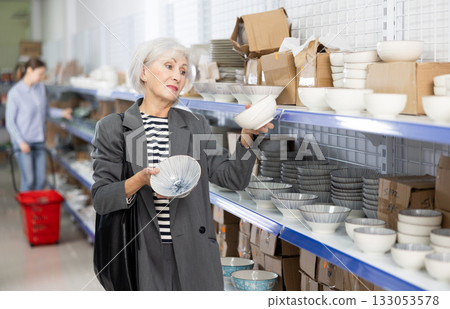 Interested senior lady choosing ceramic ramen bowls in Asian store Interested senior lady choosing ceramic ramen bowls in Asian store 133053578