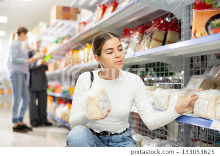 Young woman in supermarket buys daily groceries, pasta Chinese noodles Young woman in supermarket buys daily groceries, pasta Chinese noodles 133053625