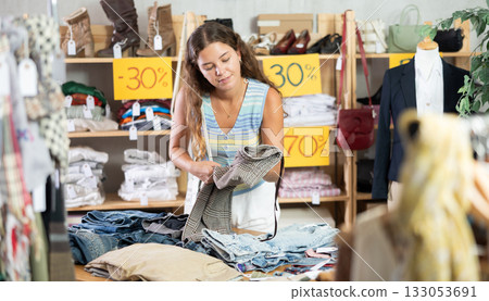 Search and selection of new jeans in a clothing store for young woman 133053691