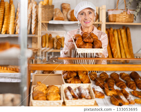 Senior female baker holds basket with finished products 133053695