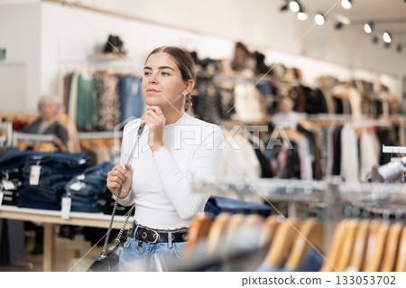 Young girl watching excitedly large stock of clothes in clothing store Young girl watching excitedly large stock of clothes in clothing store 133053702