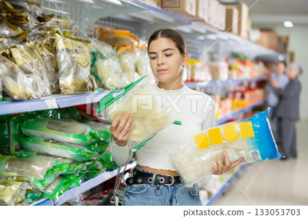 Young woman in supermarket buys daily groceries, pasta Chinese noodles 133053703