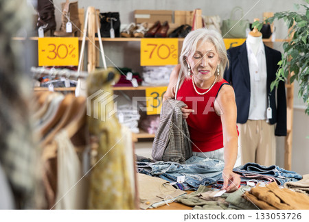 Elderly woman choosing trousers in clothing store Elderly woman choosing trousers in clothing store 133053726