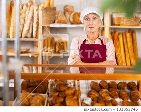 Senior female baker holds basket with finished products Senior female baker holds basket with finished products 133053740