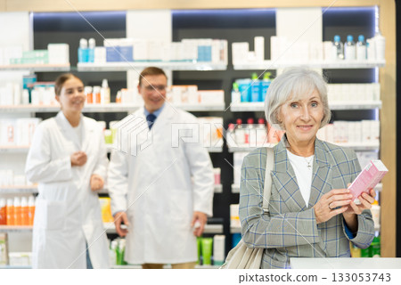 In pharmacy, senior female customer chooses cream for aging skin 133053743