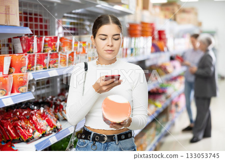 Young woman in supermarket scan QR code on instant fast food package 133053745
