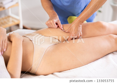 Image showcases close-up of mature female masseur hands skillfully working on things hip of woman 133053755