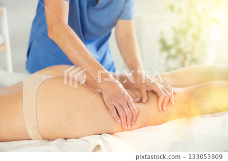 Masseuse doing thigh massage to young woman Masseuse doing thigh massage to young woman 133053809