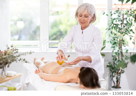 Elderly woman giving oil massage to young woman Elderly woman giving oil massage to young woman 133053814