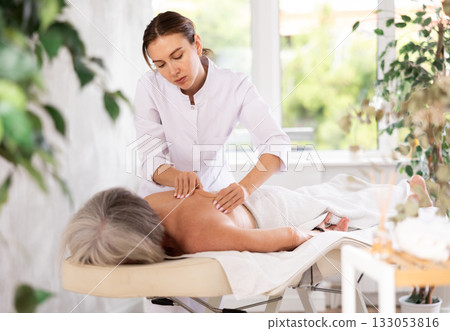 Young woman doing back massage to elderly woman Young woman doing back massage to elderly woman 133053816