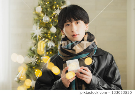 A man holding a present in front of a Christmas tree 133053830