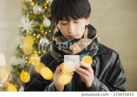 一個男人拿著禮物在聖誕樹前 133053833