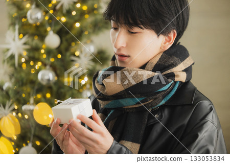 一個男人拿著禮物在聖誕樹前 一個男人拿著禮物在聖誕樹前 133053834