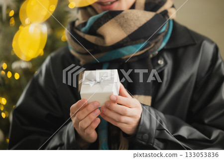 一個男人拿著禮物在聖誕樹前 133053836