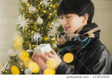 一個男人拿著禮物在聖誕樹前 133053839
