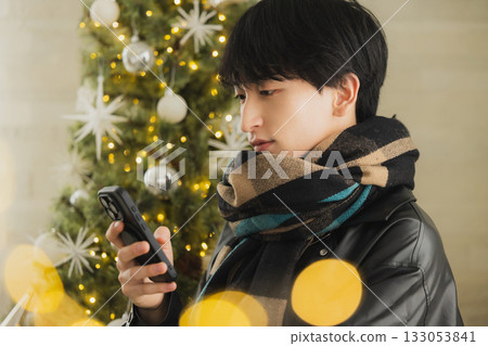 一個男人拿著禮物在聖誕樹前 一個男人拿著禮物在聖誕樹前 133053841