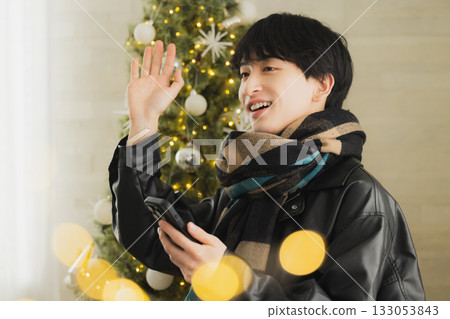 A man holding a present in front of a Christmas tree A man holding a present in front of a Christmas tree 133053843