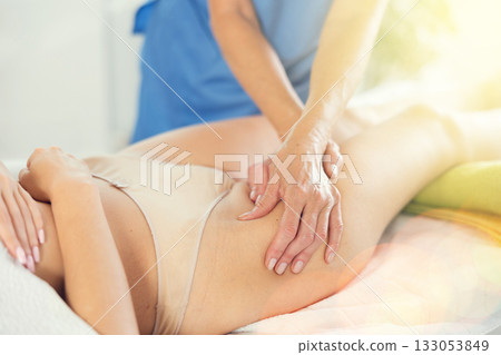 Professional massage therapist doing anti-cellulite thigh massage to woman Professional massage therapist doing anti-cellulite thigh massage to woman 133053849