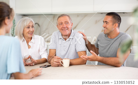 Family of four sits at table and talking Family of four sits at table and talking 133053852