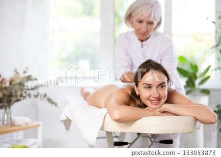 Young woman enjoying relaxing massage from professional female masseur Young woman enjoying relaxing massage from professional female masseur 133053873