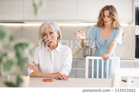 Quarrel of an mature mother and adult daughter at home. Adult daughter is unhappy with elderly mother Quarrel of an mature mother and adult daughter at home. Adult daughter is unhappy with elderly mother 133053882