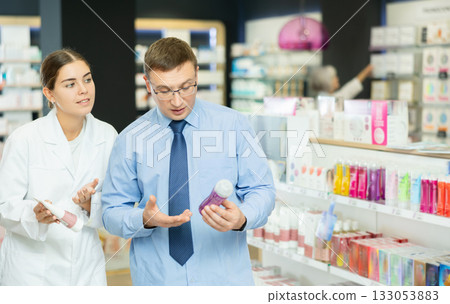 Middle-aged man choosing lubricant with help of young female pharmacist 133053883