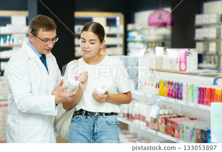 Man pharmacist helps girl buyer to decide on choice of gel for intimate hygiene. Man pharmacist helps girl buyer to decide on choice of gel for intimate hygiene. 133053897