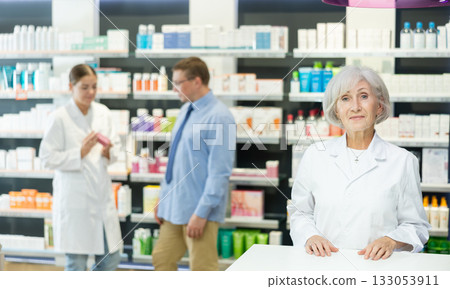 Old female pharmacist posing in chemist's shop with large assortment 133053911