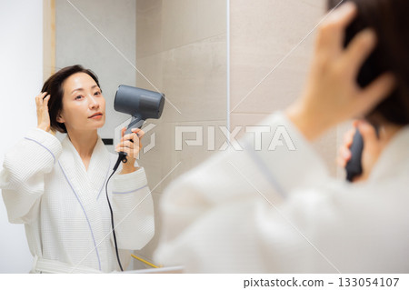 Woman using a hair dryer 133054107