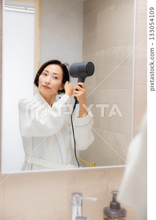 Woman using a hair dryer 133054109