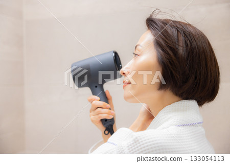 Woman using a hair dryer 133054113