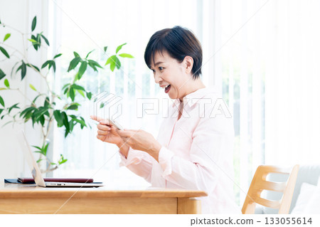 A middle-aged woman operating a smartphone A middle-aged woman operating a smartphone 133055614
