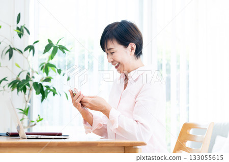 A middle-aged woman operating a smartphone 133055615